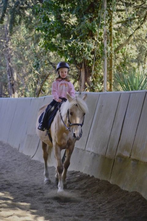 Niño montando poni con instructor
